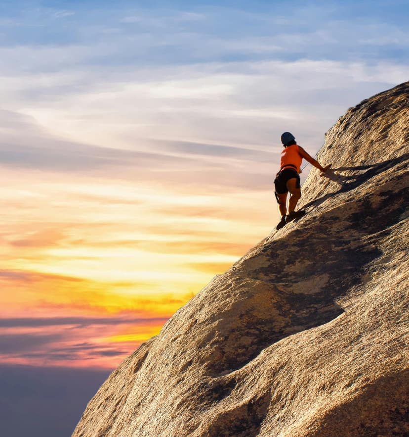 Person climbing mountain at sunset